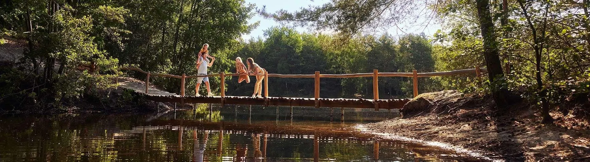 Gezin speelt op een houten brug over een vijver in het bos