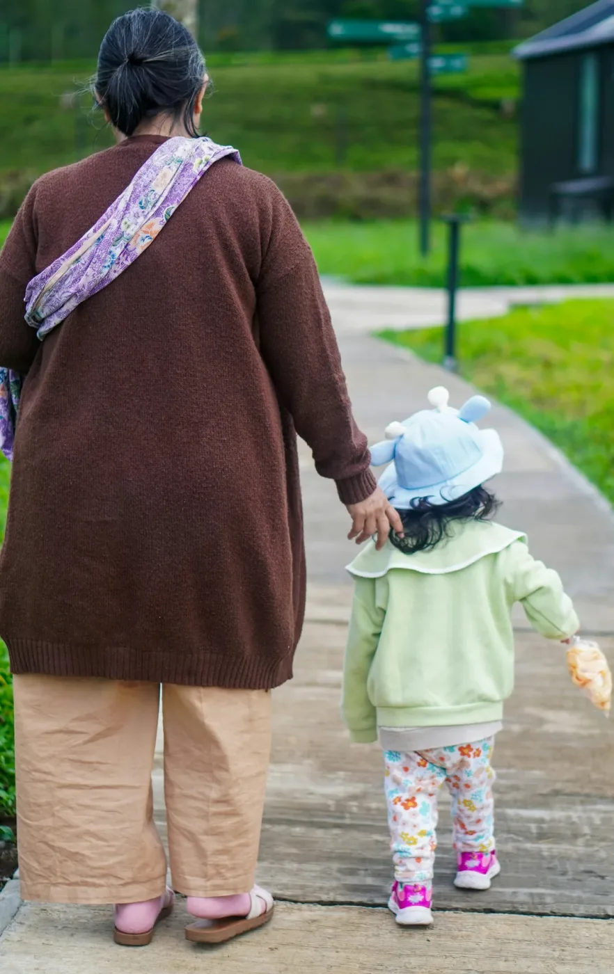 Oudere vrouw met grijs haar en een peuter wandelen samen over een pad, van achteren